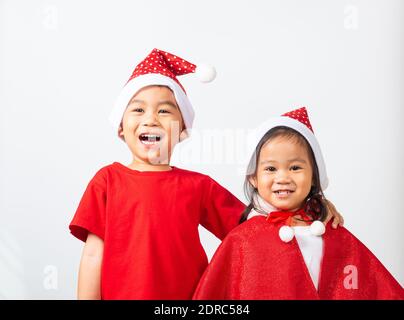 Asiatique petit mignon deux frères enfants garçon et fille sourire, les enfants vêtus de rouge chapeau de Père Noël embrassant ensemble concept de Noël Noël de Noël de vacances jour Banque D'Images