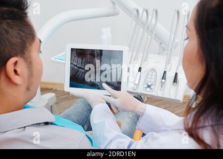 Orthodontiste montrant les rayons X de la mâchoire au patient Banque D'Images