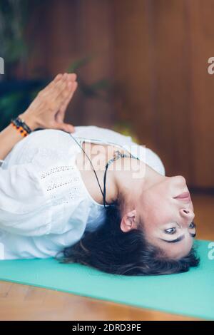 Jeune femme faisant du yoga sur le tapis d'exercice