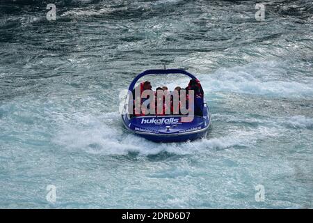 Vue de face du bateau à jet Huka Falls avec les touristes à bord dans l'eau en mouvement rapide. Banque D'Images