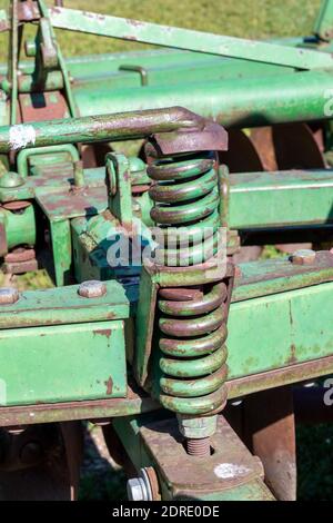 Vue rapprochée abstraite d'un grand ressort en métal un outil agricole de cultivateur de herse à disque étiré de tracteur d'époque Banque D'Images