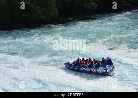 Le bateau à jet touristique des chutes Huka ralentit sur l'eau blanche de la rivière Waikato. Banque D'Images