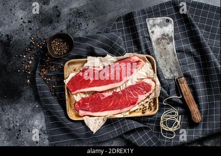 Filet de bœuf cru sur un plateau en bois. Viande de bœuf marbré. Arrière-plan noir. Vue de dessus. Banque D'Images