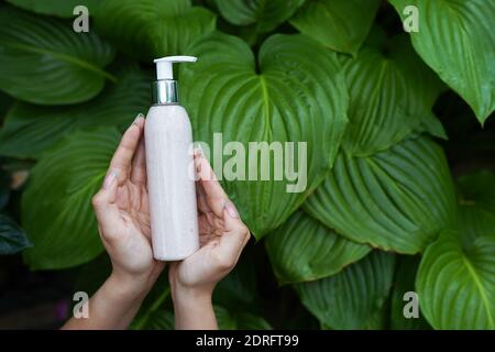 Produit de soin du corps, gommage du corps dans les mains des femmes sur fond naturel Banque D'Images