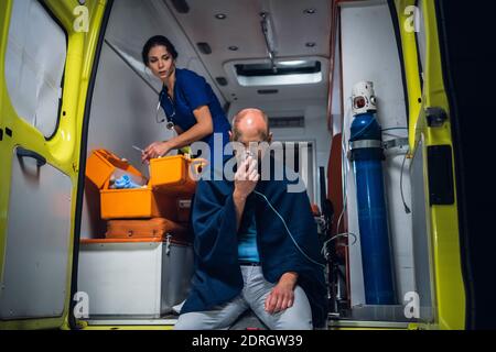 Une femme paramédique fournissant les premiers soins à un homme blessé qui a été blessé et qui a été secourée. Banque D'Images