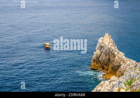 Bateau jaune sur l'eau bleu sombre de Grotta di Lord Byron près de la côte avec falaise de roche, ville de Portovenere, mer Ligurienne, Riviera di Levante, parc national C Banque D'Images