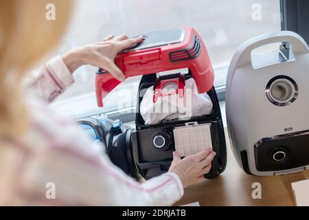 Un client blond choisit un nouvel aspirateur dans une salle d'exposition Banque D'Images