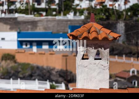 Toit de galets orange avec cheminée de style méditerranéen, bâtiments à l'arrière-plan. Banque D'Images