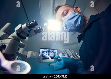 Dentiste examinant le patient avec des équipements dentaires contre la chirurgie dentaire moderne avec la radiographie et le microscope. Banque D'Images