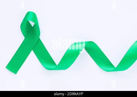 Ruban vert émeraude ou vert jade gondolé sur fond de tissu blanc avec espace de copie, symbole de sensibilisation au cancer du foie, Journée mondiale du cancer. Soins de santé ou Banque D'Images