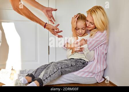 femme avec fille assis souffrant de cruauté du père, concept de relations abusives, l'homme crie et punit les membres de la famille Banque D'Images