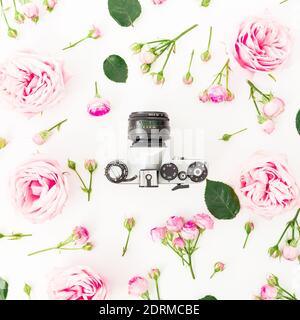 Cadre fleuri avec roses roses roses roses et ancien appareil photo rétro sur fond blanc. Flat lay, vue de dessus. Banque D'Images