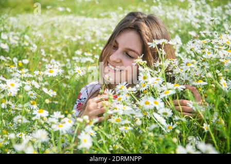 Gros plan portrait d'une charmante jeune femme romantique avec fond de champ de fleurs de camomille, été. Banque D'Images