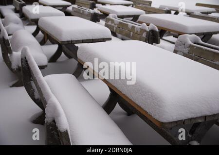 Des tas épais de neige fraîche sur des tables et des bancs en bois devant une cabane de ski par une journée. Banque D'Images