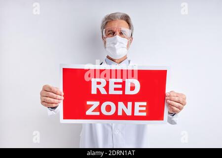 texte écrit zone rouge et docteur homme dans un costume blanc noismat isolé sur fond blanc studio, homme âgé regarde la caméra Banque D'Images