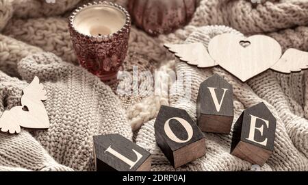 Les lettres en bois composent le mot amour sur un fond d'articles tricotés confortables. Concept de vacances de la Saint-Valentin. Banque D'Images