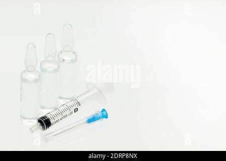 Ampoules de médecine en verre avec seringue liquide et en plastique avec aiguille, isolées sur fond blanc Banque D'Images