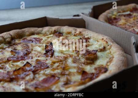 Vue rapprochée de deux pizzas sur des boîtes en carton. Pizza Carbonara avec oignon et bacon caramélisés et pizza hawaïenne. Banque D'Images