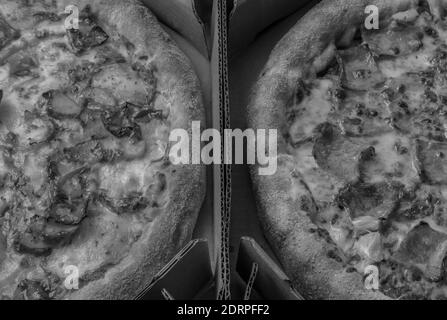 Vue rapprochée de deux pizzas sur des boîtes en carton.vue en haut de la pizza hawaïenne et Carbonara avec fromage, oignon caramélisé et bacon.style noir et blanc Banque D'Images