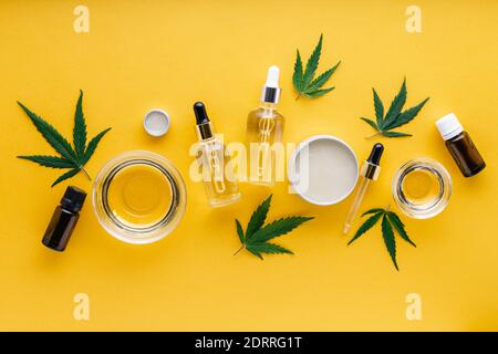 Variétés d'huiles de chanvre CBD, huile essentielle, beurre de sérum. Teinture de chanvre. Mettre les produits cosmétiques de cannabis avec du cannabis médical sur fond jaune Banque D'Images