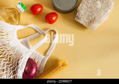 Articles alimentaires dans un sac à ficelle sur fond jaune avec un espace pour le texte. Livraison de nourriture. Banque D'Images