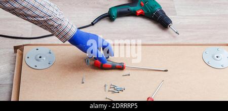 Processus d'assemblage de meubles par des mains mâles dans des gants, maître recueille les meubles de table à l'aide d'outils de tournevis, instrument de forage. Déplacement, à la maison Banque D'Images