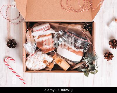 Boîte cadeau de Noël avec mélange de biscuits et boisson au chocolat dans un pot en verre sur une table en bois sombre. Couches de farine, poudre de cacao, sucre. Ingrédients pour le gingembre Banque D'Images