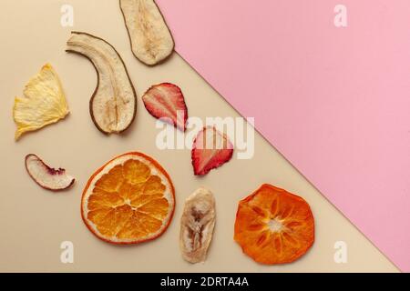 Croustilles de fruits séchées sur fond rose. Le concept d'en-cas sain sans sucre, dessert pour les végétariens. Copier l'espace. Banque D'Images