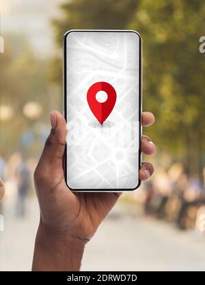 Smartphone avec application GPS ouverte avec la fonction Pinpoint rouge en noir Main femelle Banque D'Images