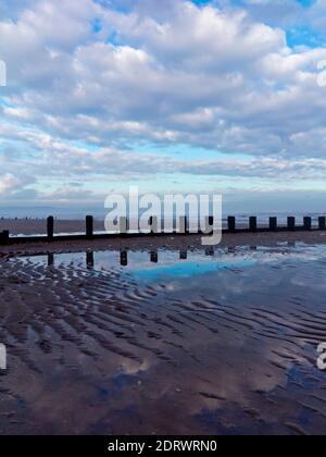 Vue d'hiver sur la plage à Bridlington une station balnéaire populaire dans l'East Riding of Yorkshire England UK avec le ciel reflété dans l'eau de mer. Banque D'Images