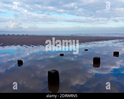 Vue d'hiver sur la plage à Bridlington une station balnéaire populaire dans l'East Riding of Yorkshire England UK avec le ciel reflété dans l'eau de mer. Banque D'Images