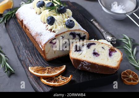 Gâteau piese maison avec crème de biscuit décorée de citron et de myrtille. Sur panneau en bois sur fond gris. Gros plan Banque D'Images