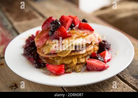 Crêpes maison de style américain servies avec du miel et des fruits congelés décongelés. Angleterre GB Banque D'Images