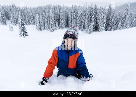 Jour d'hiver, beaucoup de neige, un garçon souriant qui pose dans la neige Banque D'Images