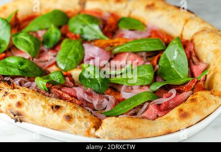 Pizza au rôti de bœuf, tomates séchées, oignons marinés et épinards. Cuisine italienne Banque D'Images