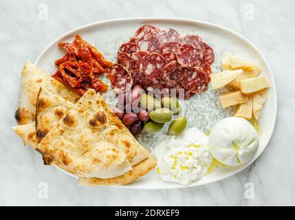 Plateau d'antipasti avec différents fromages, viandes et focaccia sur fond de marbre. En-cas italien Banque D'Images