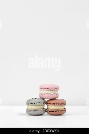 trois macarons français ou macarons de couleur rose, marron et gris sur fond blanc. Banque D'Images