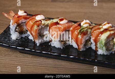 Un gros plan de sushi farci de crevettes recouvertes de saumon et d'avocat. Banque D'Images