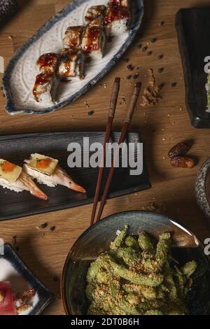 Un cliché vertical d'une variété de sushis et de nigiri et de salade wakame sur table servis dans des assiettes en céramique. Banque D'Images
