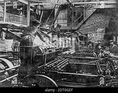 Début des années 1900, photo d'archive en noir et blanc montrant les presmen et enfants travaillant sur des presses lithographiques dans la salle des presses / impression boutique Banque D'Images