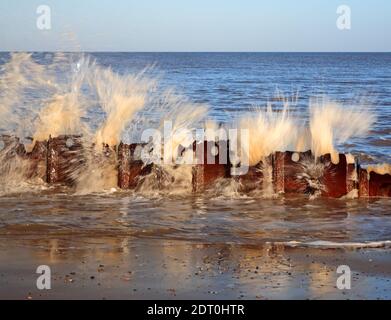 Une étude en mouvement de vagues frappant les restes de défenses de la vieille mer à Cart Gap, Happisburgh, Norfolk, Angleterre, Royaume-Uni. Banque D'Images