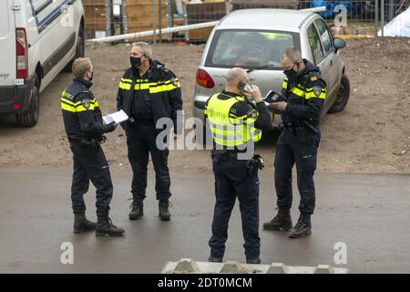 ZUTPHEN, PAYS-BAS - 08 décembre 2020 : les policiers en masques délibèrent et organisent sur une scène d'accident avec des carnets et un téléphone portable en ha Banque D'Images