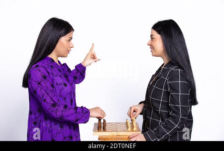 Les jumeaux jouent aux échecs sur fond blanc. Une des filles pointe vers le haut, sa première déménagement. Concept de jeu noir et blanc Banque D'Images