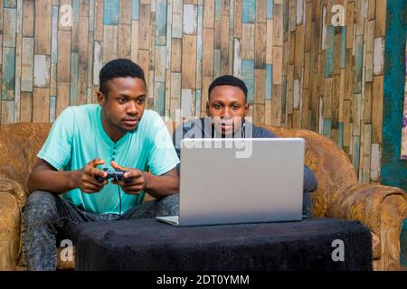 jeunes hommes noirs jouant à un jeu vidéo sur un ordinateur portable à la maison Banque D'Images