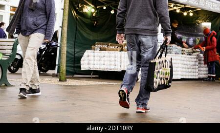 Deux hommes anonymes marchant à travers un marché de rue en plein air, un portant UN sac de Waitrose pour la vie Banque D'Images