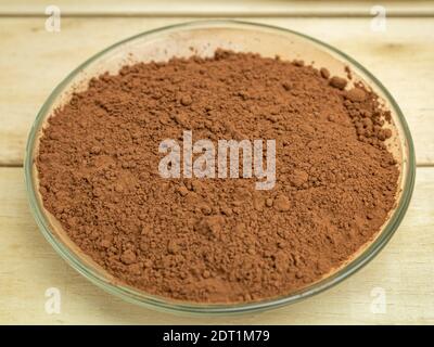 Poudre de cacao dans une plaque de verre sur fond de bois Banque D'Images