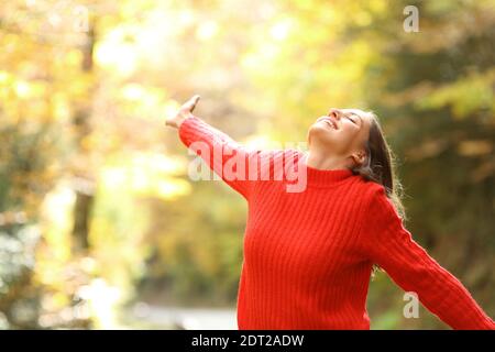 Femme excitée en rouge célébrant des vacances dans une forêt en automne Banque D'Images