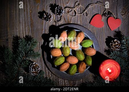 Biscuits aux noix avec Dulce de Leche ou lait condensé. Lumière naturelle, ombres longues. Brindilles de sapin décorées de cônes de pin, d'une bougie rouge et d'un coeur en bois Banque D'Images