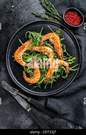 Crevettes géantes grillées, crevettes, arugula et épices. Arrière-plan noir. Vue de dessus. Banque D'Images