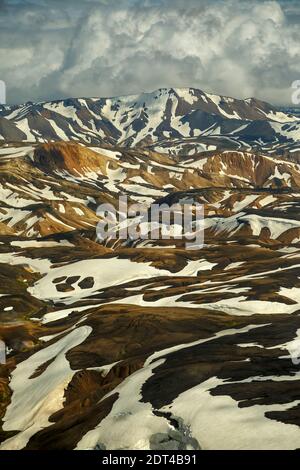 Vue aérienne de montagnes de rhyolite partiellement couvert de neige, la Réserve Naturelle de Fjallabak, Landmannalaugar, Islande Banque D'Images